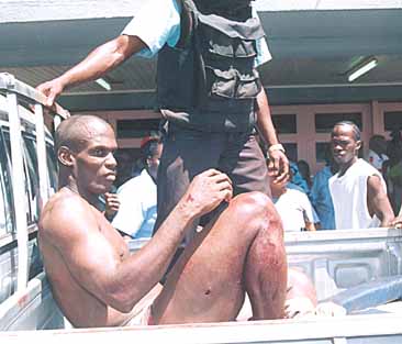A sullen, but subdued Solomon Blackman arrives at the Georgetown Public Hospital in a Police vehicle after killing two Policemen and wounding another two at the Brickdam Police Station.