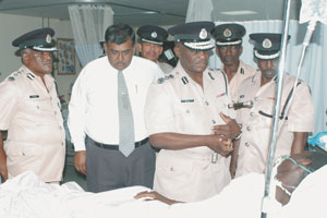 Commissioner of Police, Mr. Winston Felix comforts the injured rank. Felix is flanked by (from left) Deputy Commissioner Edward Wills, Minister of Home Affairs, Ronald Gajraj and Assistant Commissioner `A Division, Larry George. (Picture by Quacy Sampson)