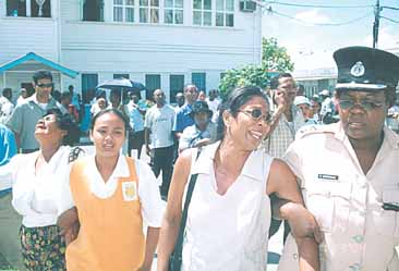 The mother, daughter and wife of Lance Corporal Ramnarine Lachana are consoled by a Police Officer.